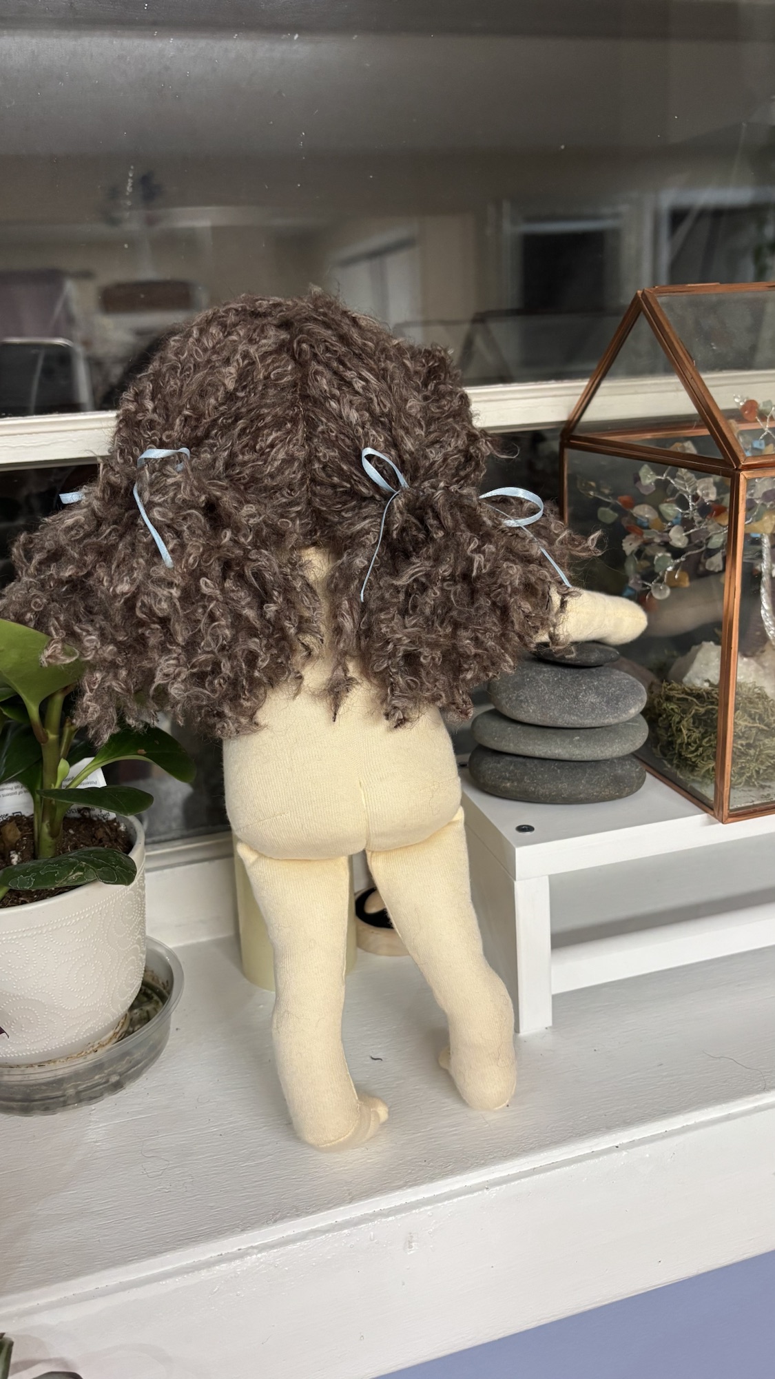 Back view of a handmade doll showing hand-styled yarn hair.