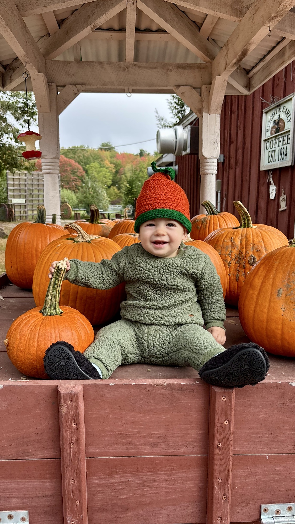 Child wearing a handmade green knit set and pumpkin hat.