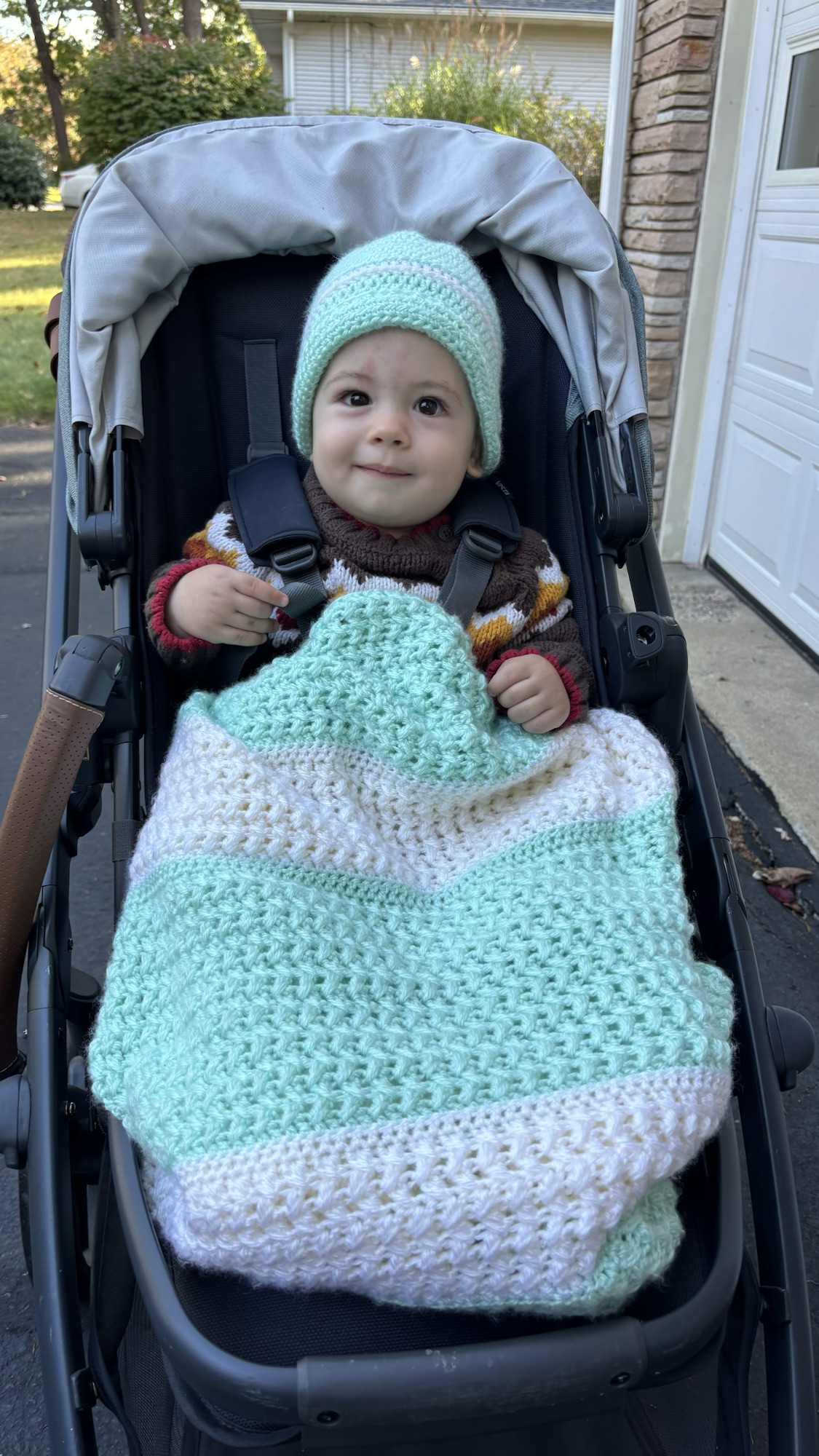 Baby wearing a handmade mint crochet hat with a matching blanket.