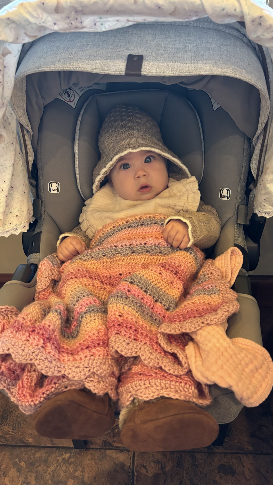 Baby bundled in a handmade striped crochet blanket, hat, and mittens.
