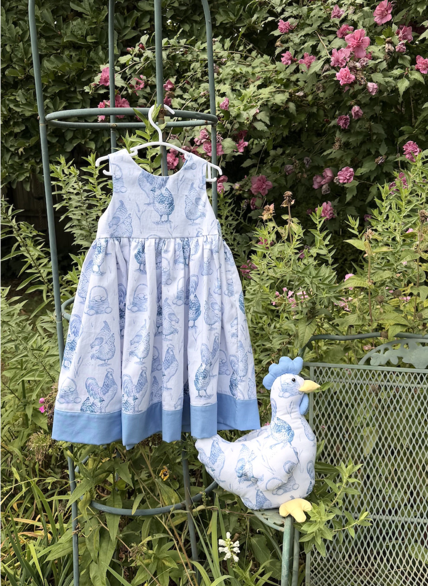 Handmade blue chicken-print dress displayed with a matching textile chicken.