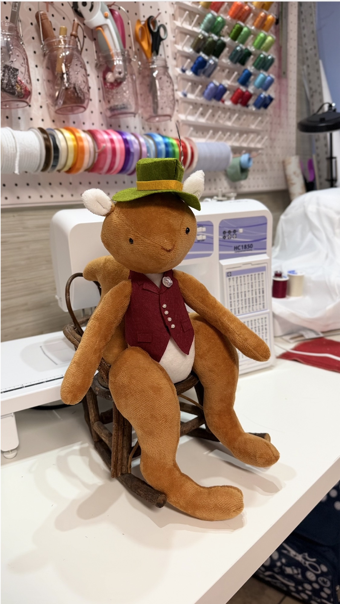 Handmade brown bear character wearing a green hat and burgundy vest.