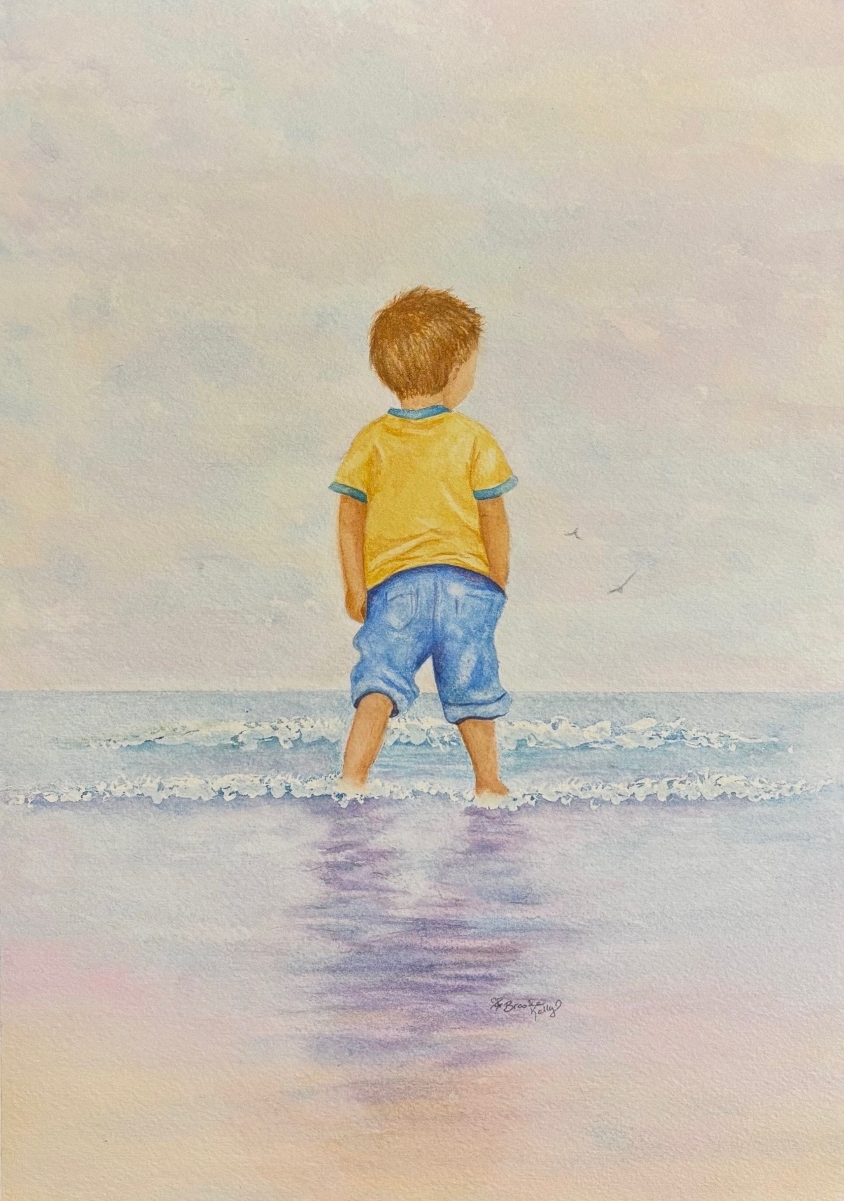 Watercolor painting of a child standing at the ocean with waves at his feet.