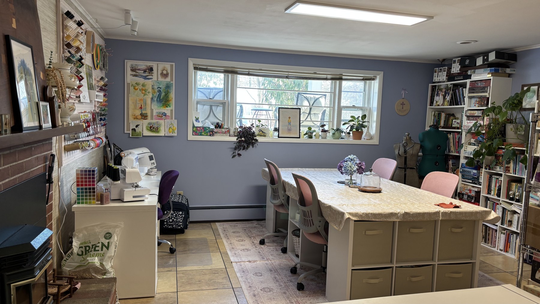 Bright art studio room with large worktables, storage shelves, and natural light.